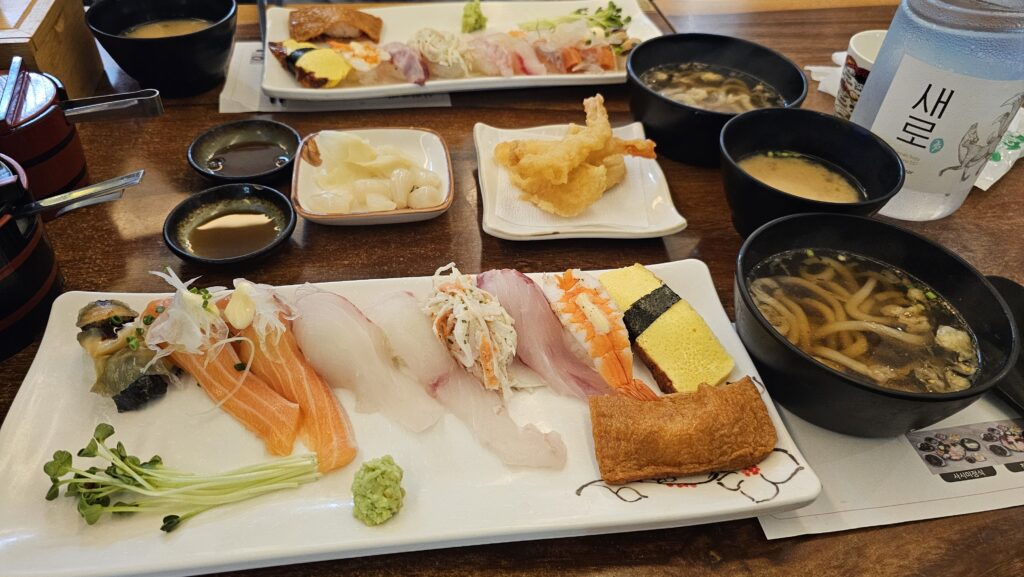 Full table setting for two at Shinhee Sushi Yeouido with two sushi platters tempura udon and miso soup

