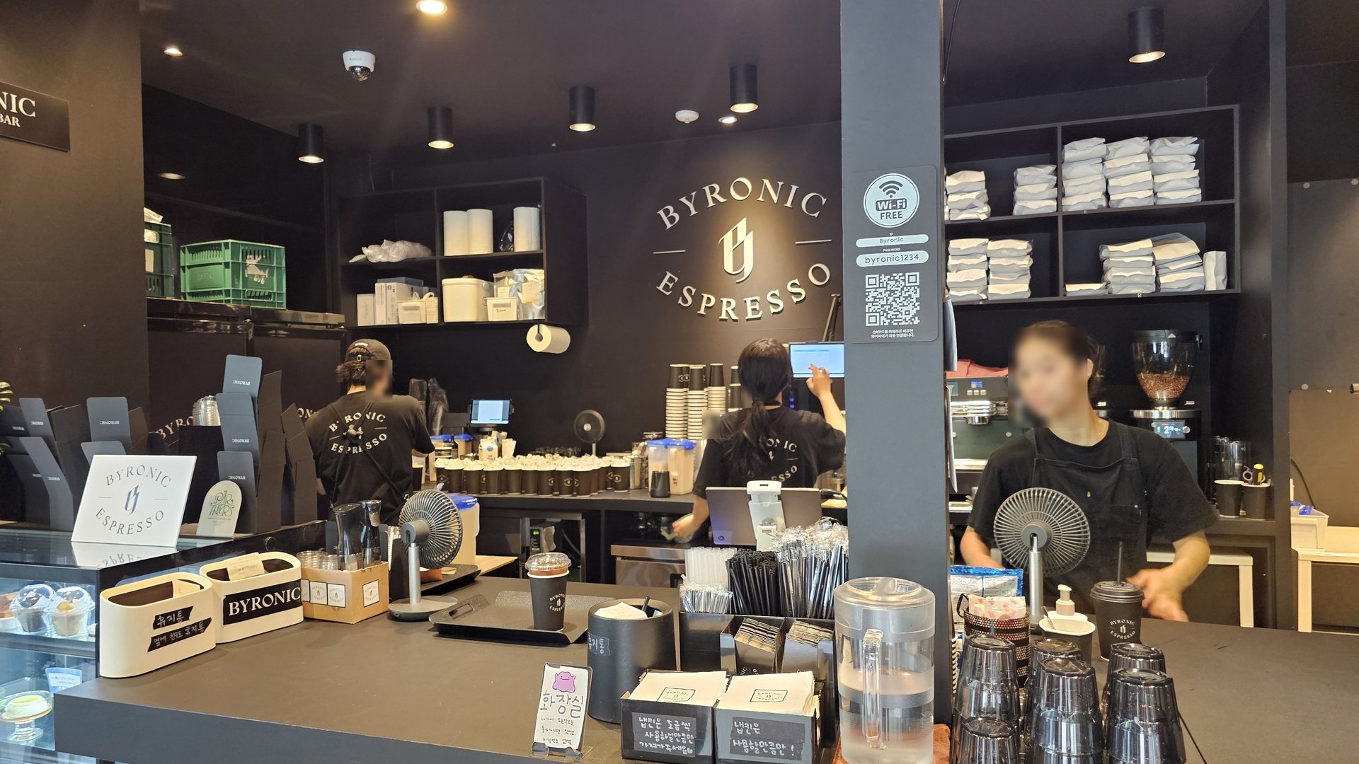 Byronic Espresso Yeouido counter with three baristas and BYRONIC ESPRESSO logo engraved on black wall