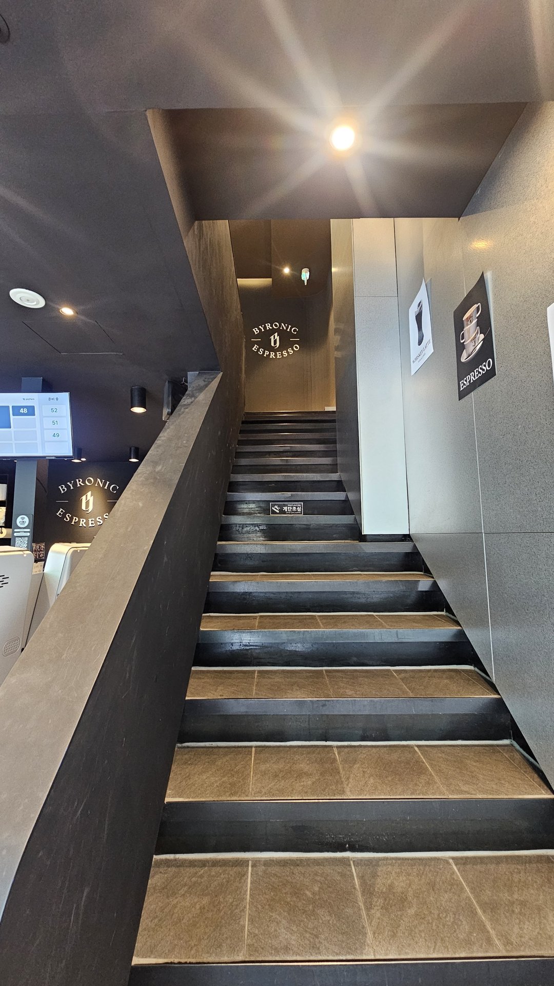 Multi-level mezzanine interior of Byronic Espresso Yeouido with black vertical louver panels and large brand logo sign