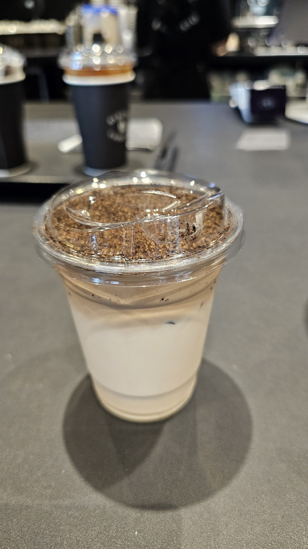 Close-up of Byronic Espresso signature iced latte with white milk layer topped with coffee crumble crust