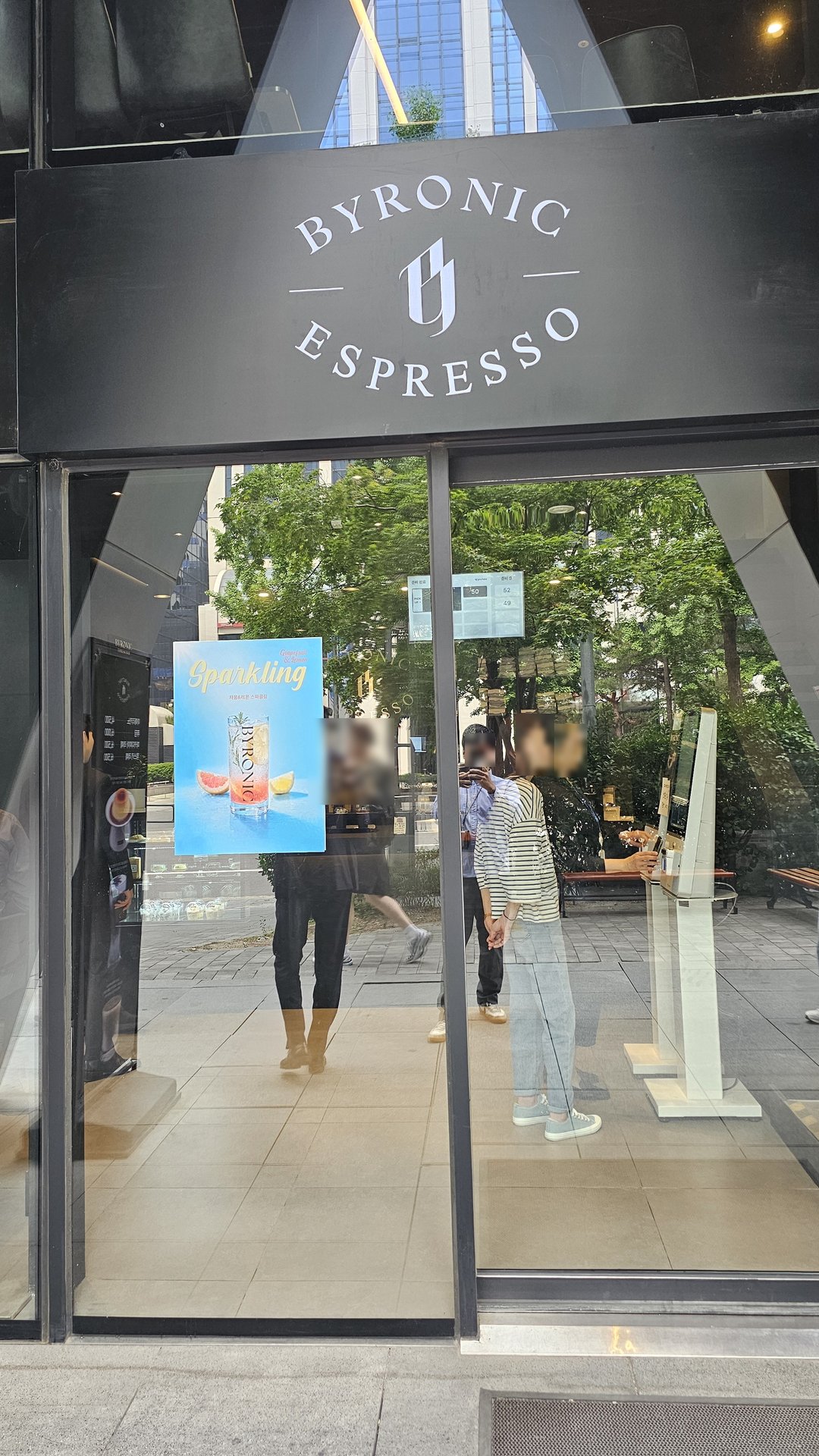 Glass facade exterior of Byronic Espresso Yeouido with logo engraved on floor-to-ceiling windows and Sparkling drink poster