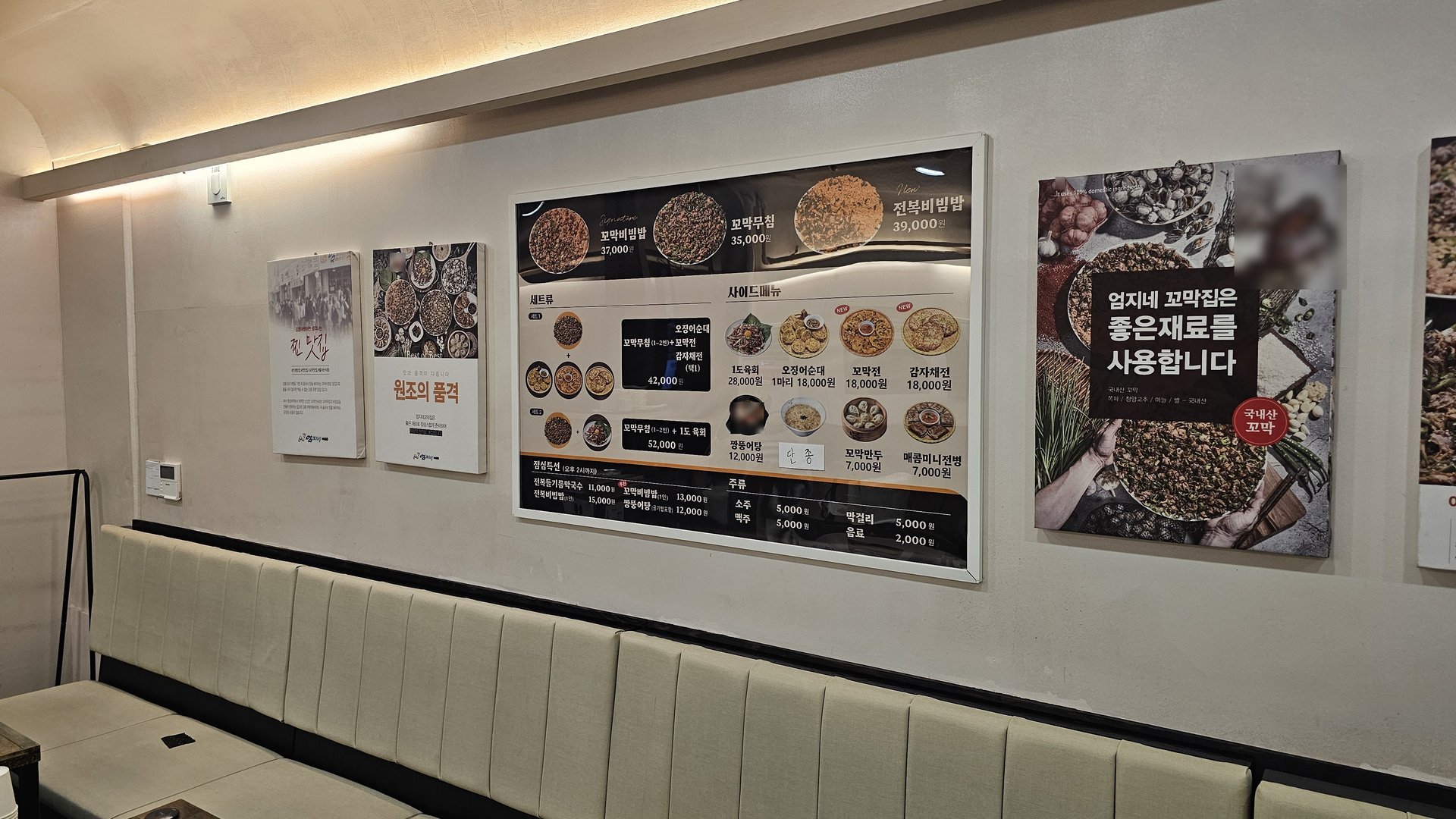 Wall menu at Eomjine Kkomak House showing prices for kkokak bibimbap, kkokak muchim, and abalone bibimbap