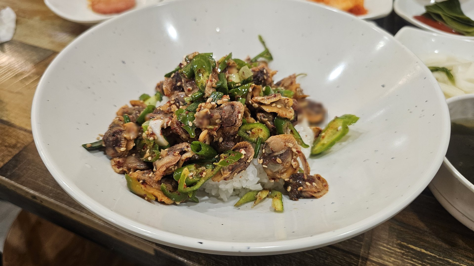 Kkokak bibimbap topped with a large mound of seasoned cockles, sesame, and green onions at Eomjine Kkomak House