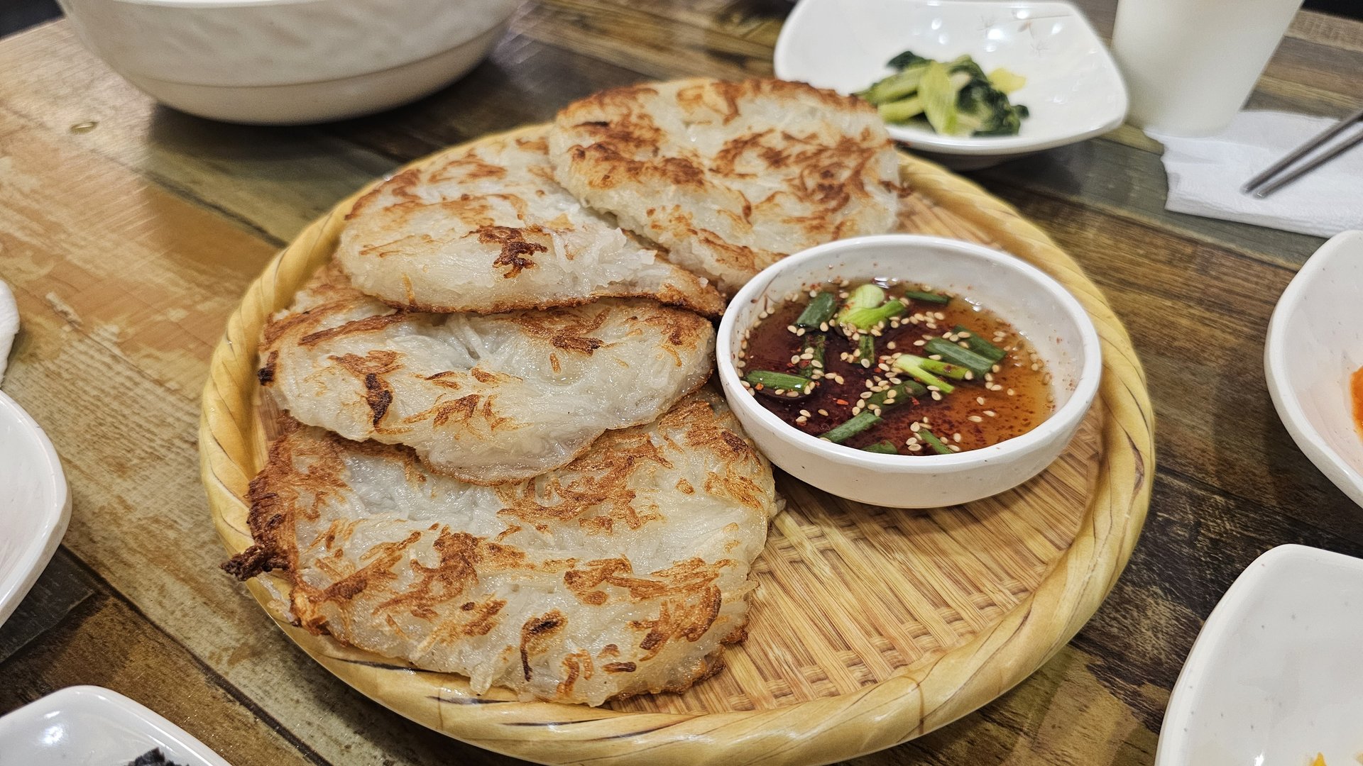 Crispy potato jeon (Korean savory pancake) on bamboo tray with soy dipping sauce at Eomjine Kkomak House