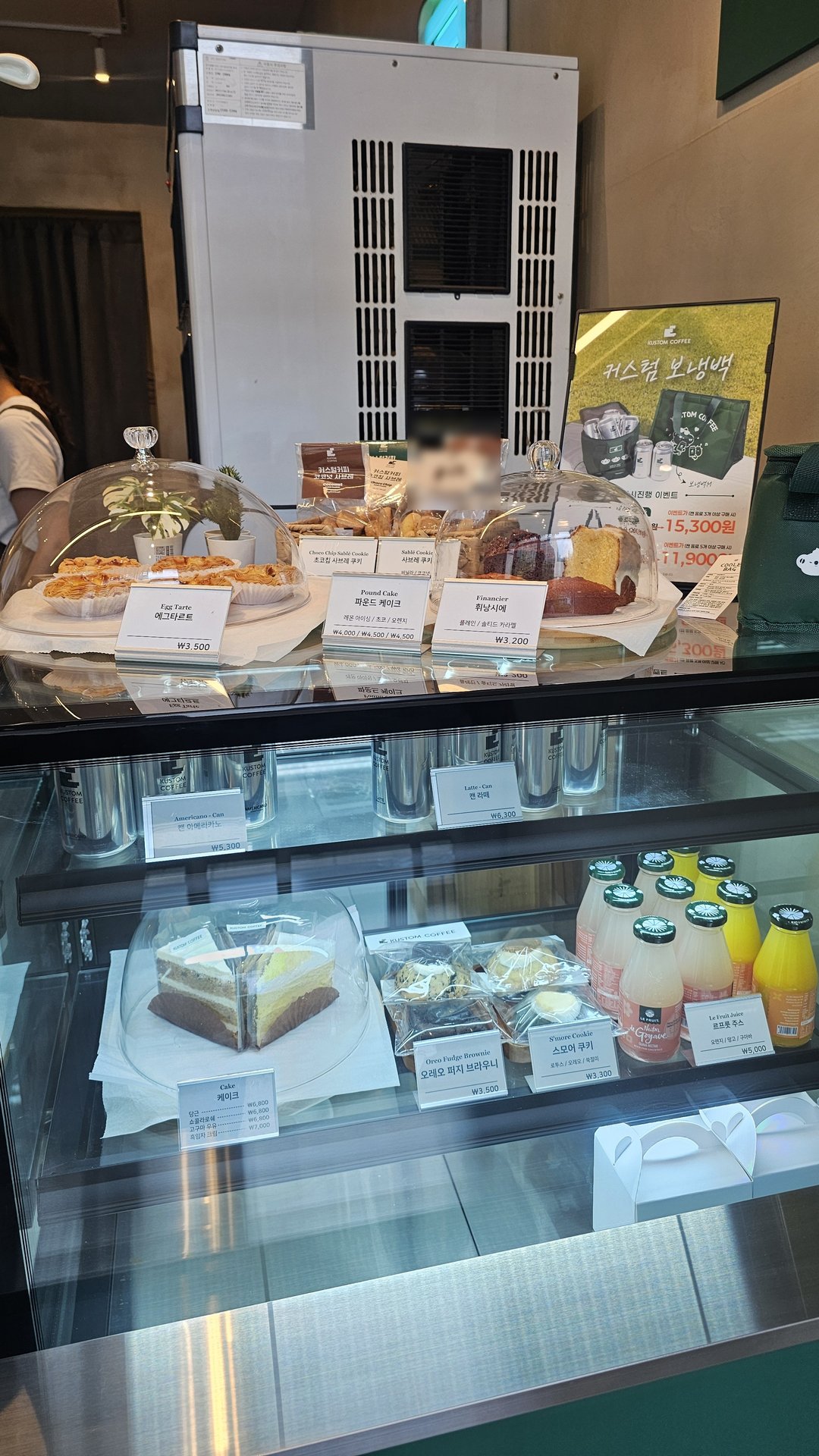 Dessert display case at Kustom Coffee Yeouido with cake slices scones and bottled drinks