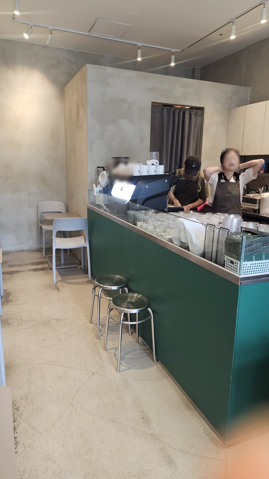 Dark green countertop interior at Kustom Coffee Yeouido with two staff members serving customers