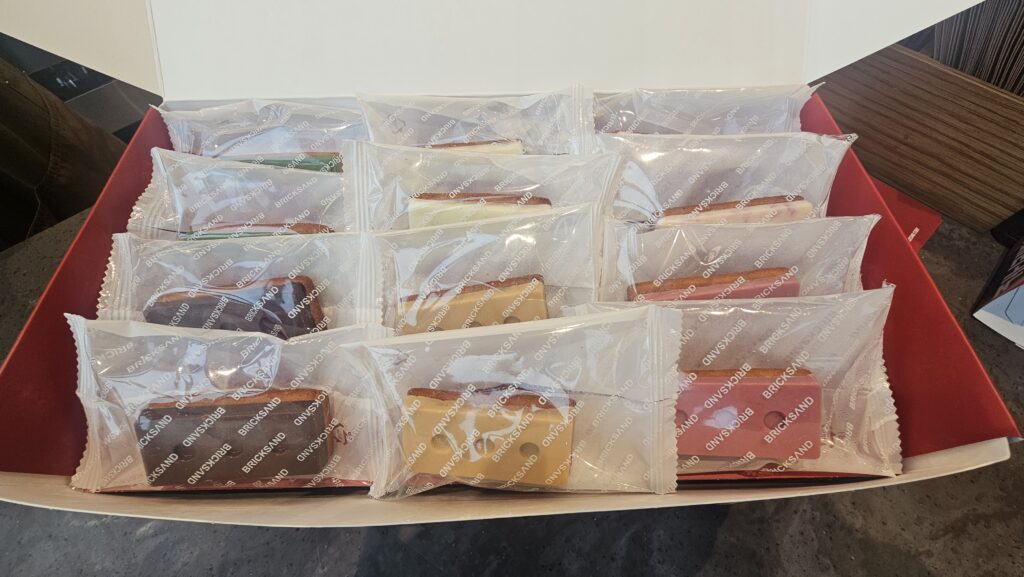 Opened Bricksand 24-piece gift box viewed from above showing individually wrapped brick cookies in assorted flavors