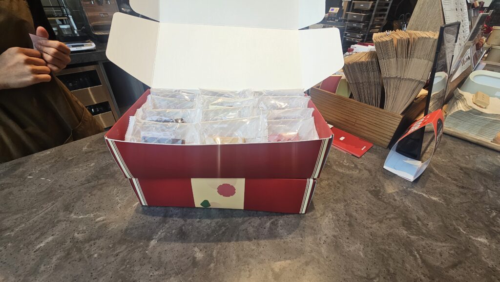 Receiving a Bricksand Seoul red gift box with open lid at the Yeouido cafe counter with staff hand visible