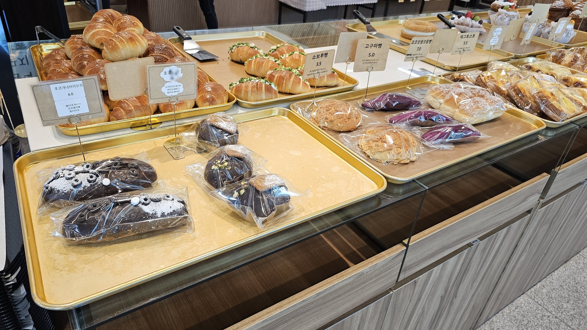 Chocolate-coated bread, red bean bread, and cream bread on individual trays at Mochang-po Bread Cafe
