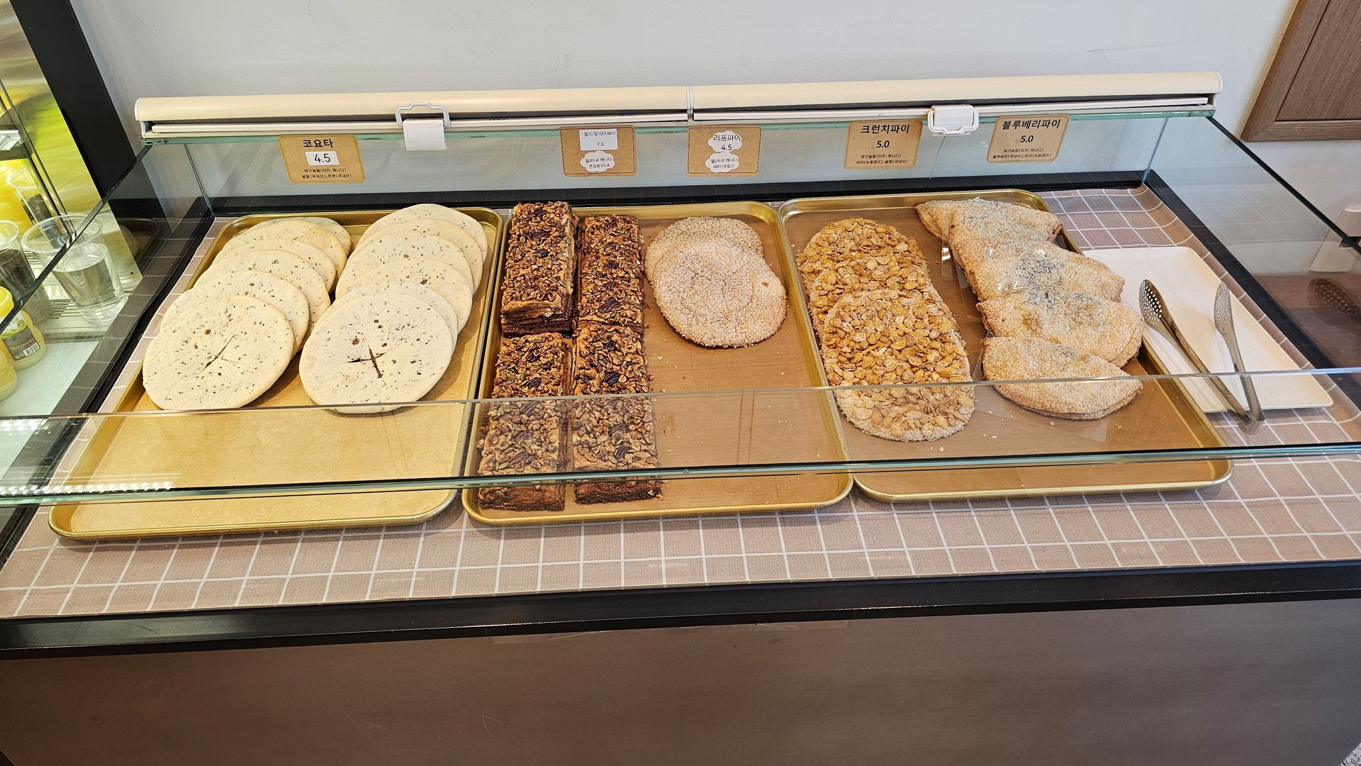 Glass showcase with Coyota seed bread at 4500 KRW, crunch pie, and blueberry pie at Mochang-po Bakery