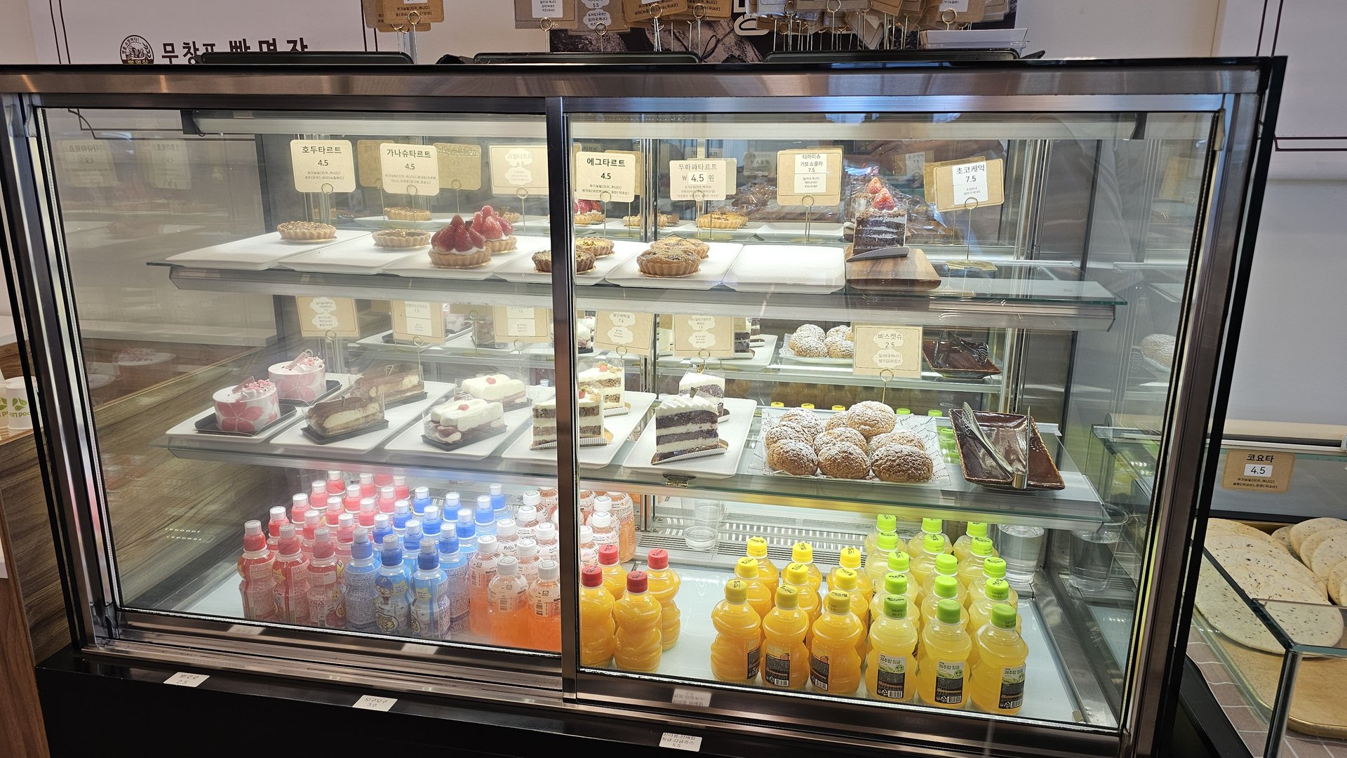 Refrigerated showcase with whole cakes and colorful drink bottles at Mochang-po Bread Cafe