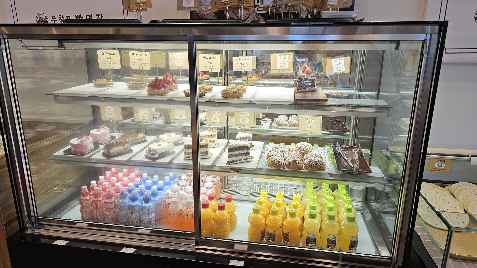 Refrigerated display case with cakes, donuts, cookies, and drinks at Mochang-po Bakery Cafe