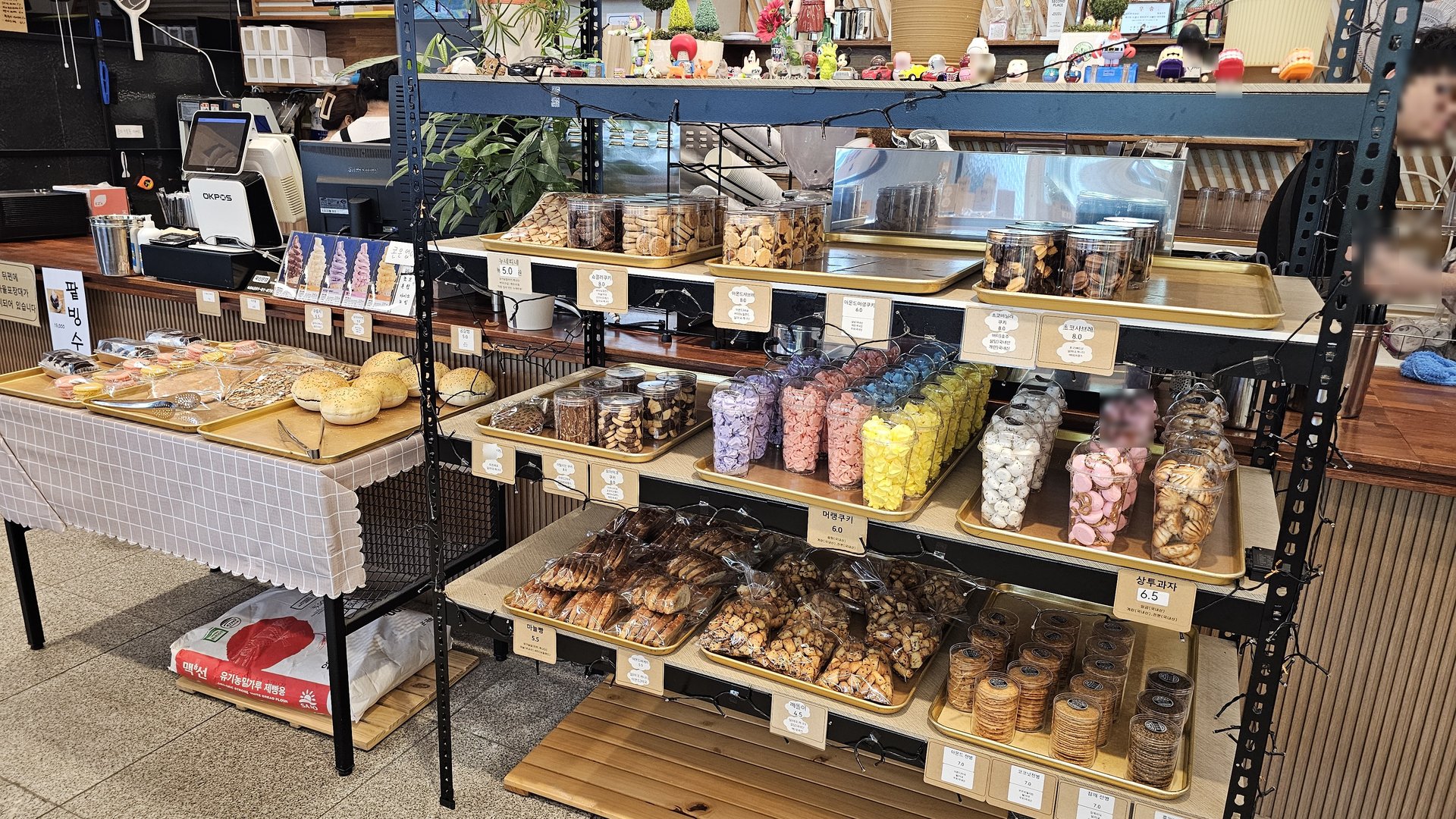 Counter shelf with macarons, cookie jars, and packaged candy snacks at Mochang-po Bread Cafe