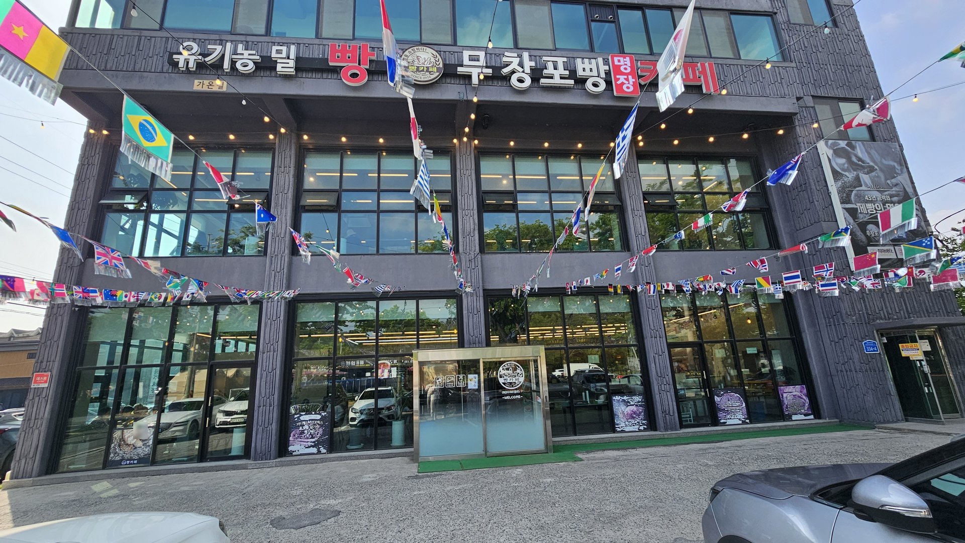 Exterior of Mochang-po Bread Cafe building with organic wheat bread signage and flags from multiple countries