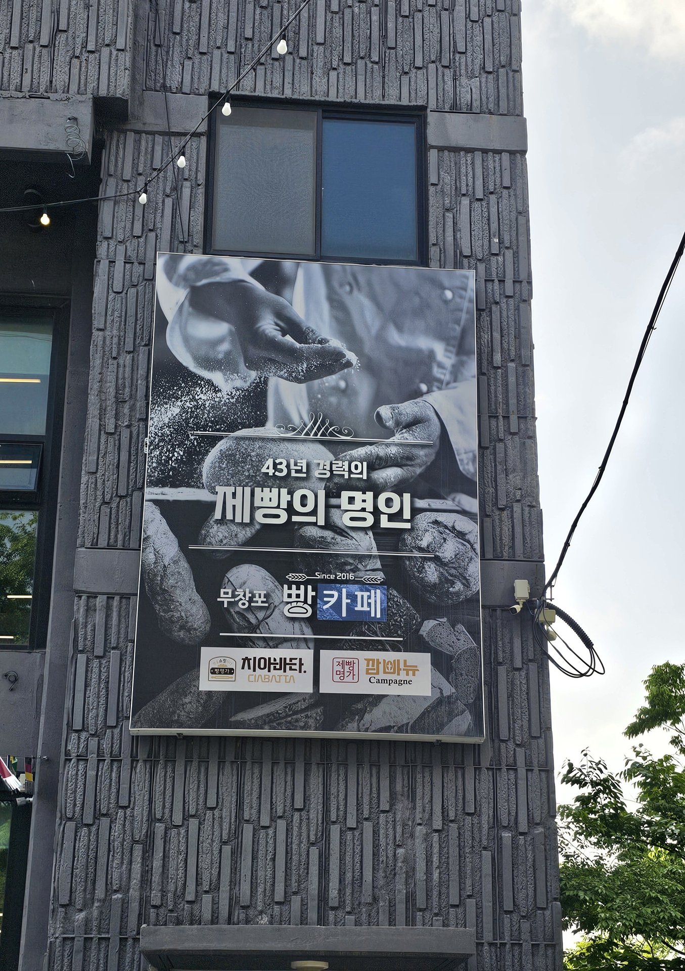 Large exterior sign for Mochang-po Bread Cafe stating 43 years master baker experience since 2018 with ciabatta and campagne logo