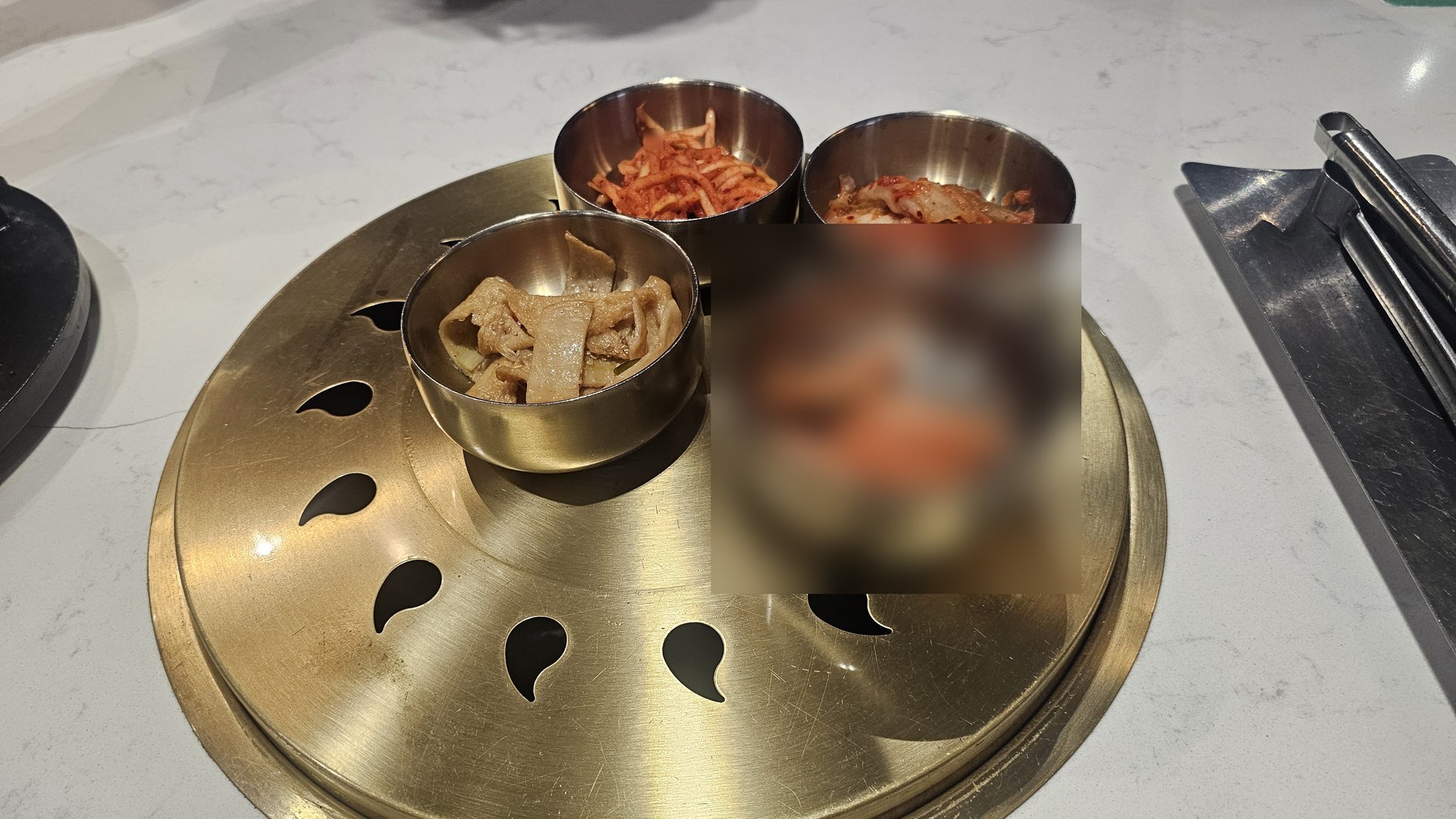Four-piece banchan set on a gold tray at Shindosegi Yeouido — kkakdugi, baechu kimchi, jeotgal, and jangajji