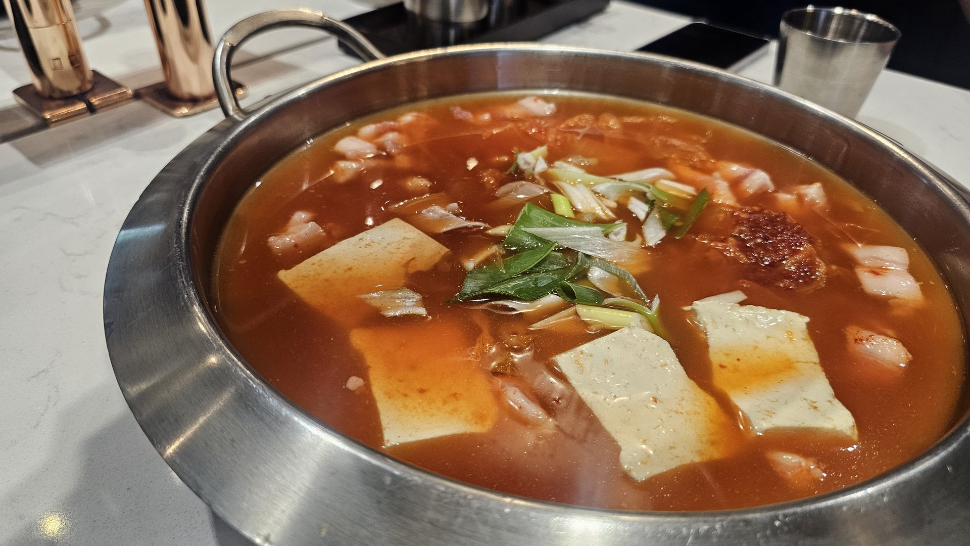 Kimchi jjigae hot pot before boiling with tofu, kimchi, green onion, and seasoning at Shindosegi