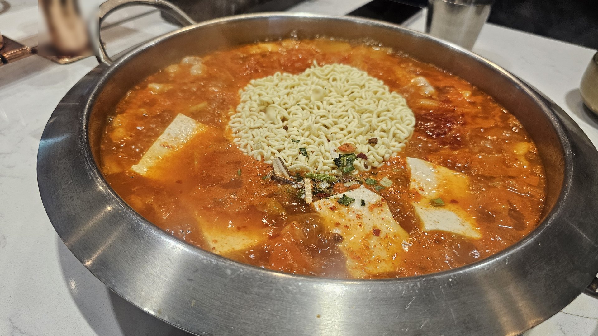 Kimchi jjigae with ramen noodle add-on starting to boil at Shindosegi Yeouido