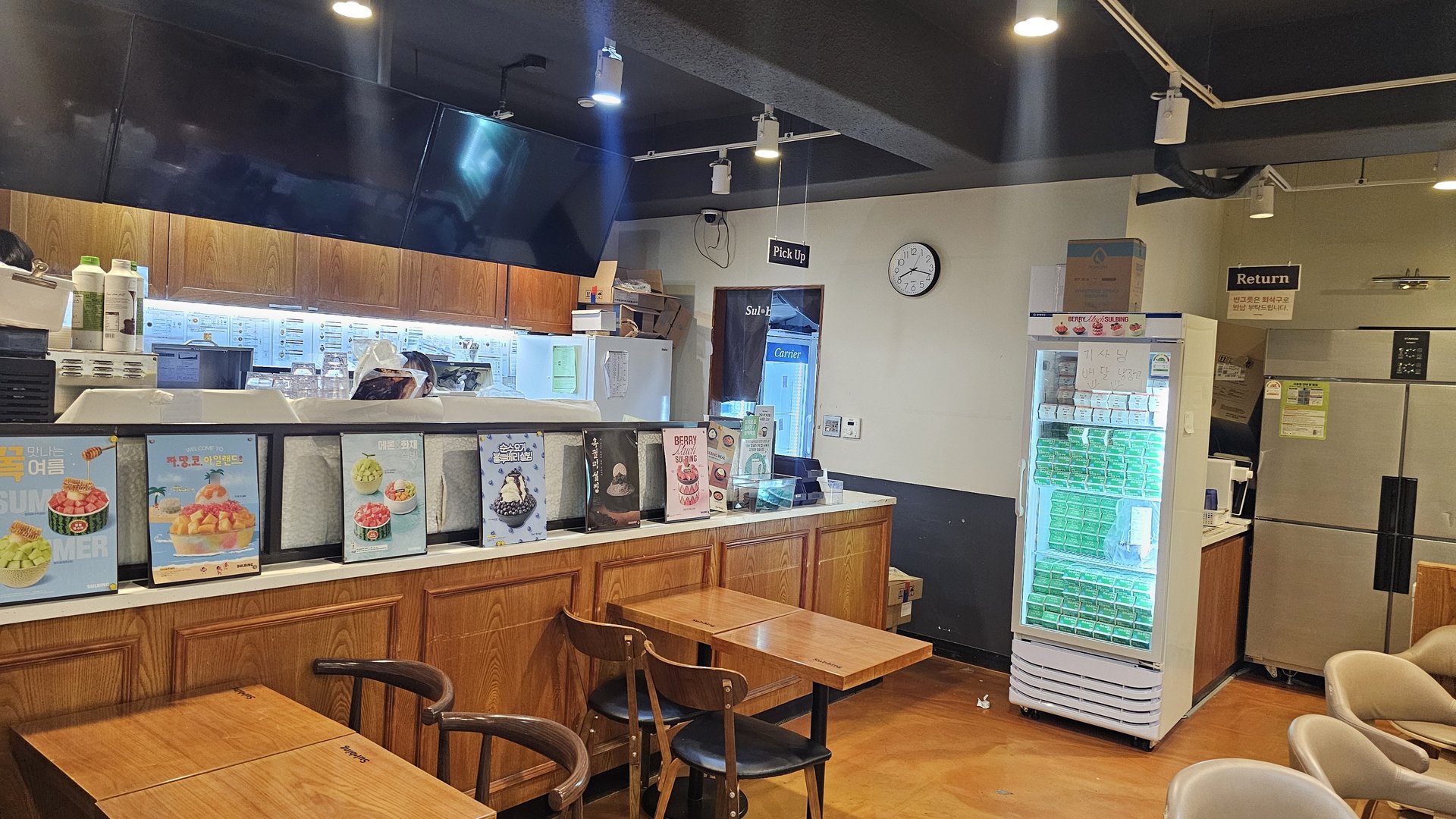 Interior counter and pickup area at Sulbing Gocheok with menu posters and drink fridge