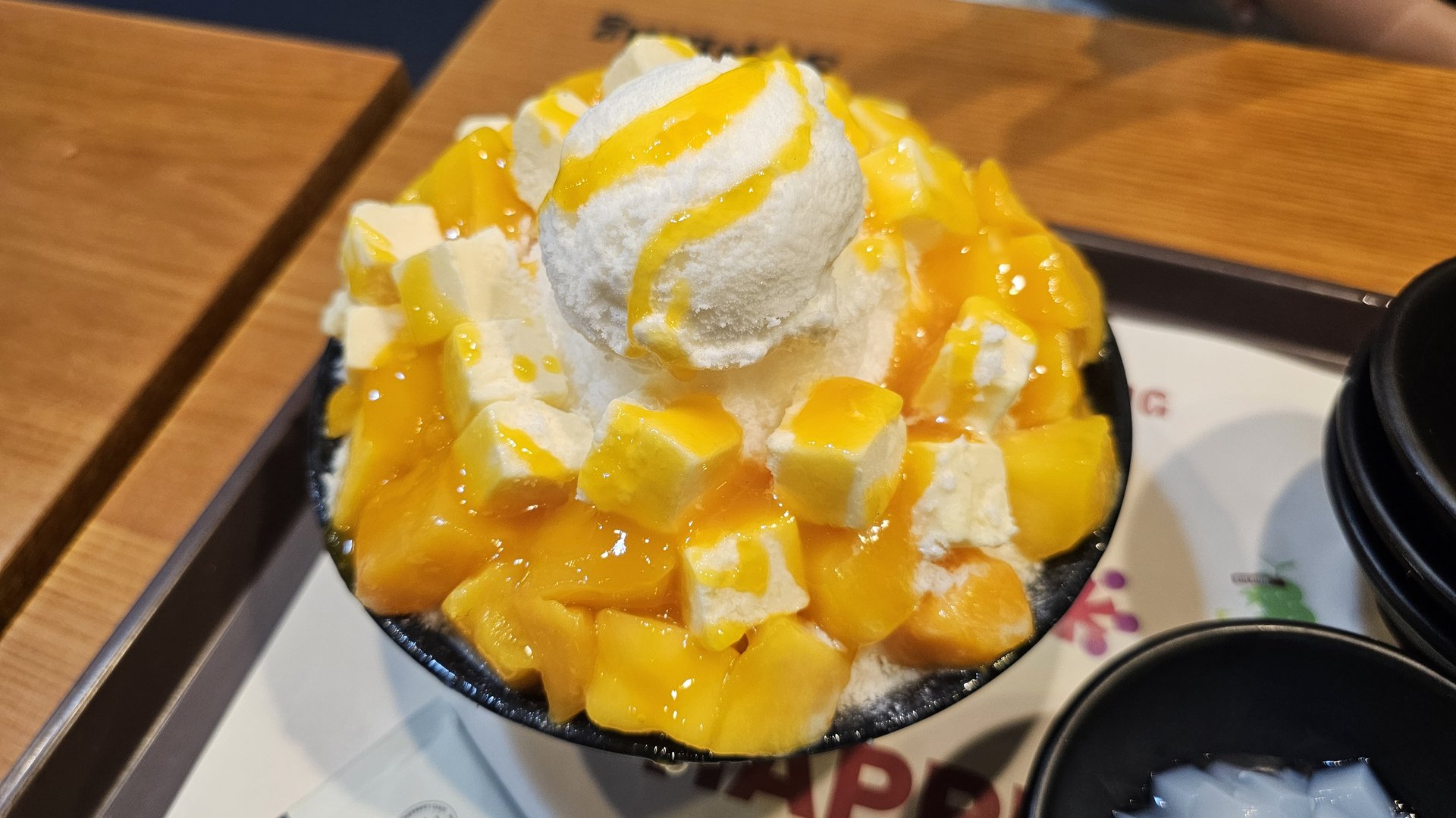 Apple mango cheese bingsu close-up showing mango cubes cheese cream ice cream scoop and mango sauce