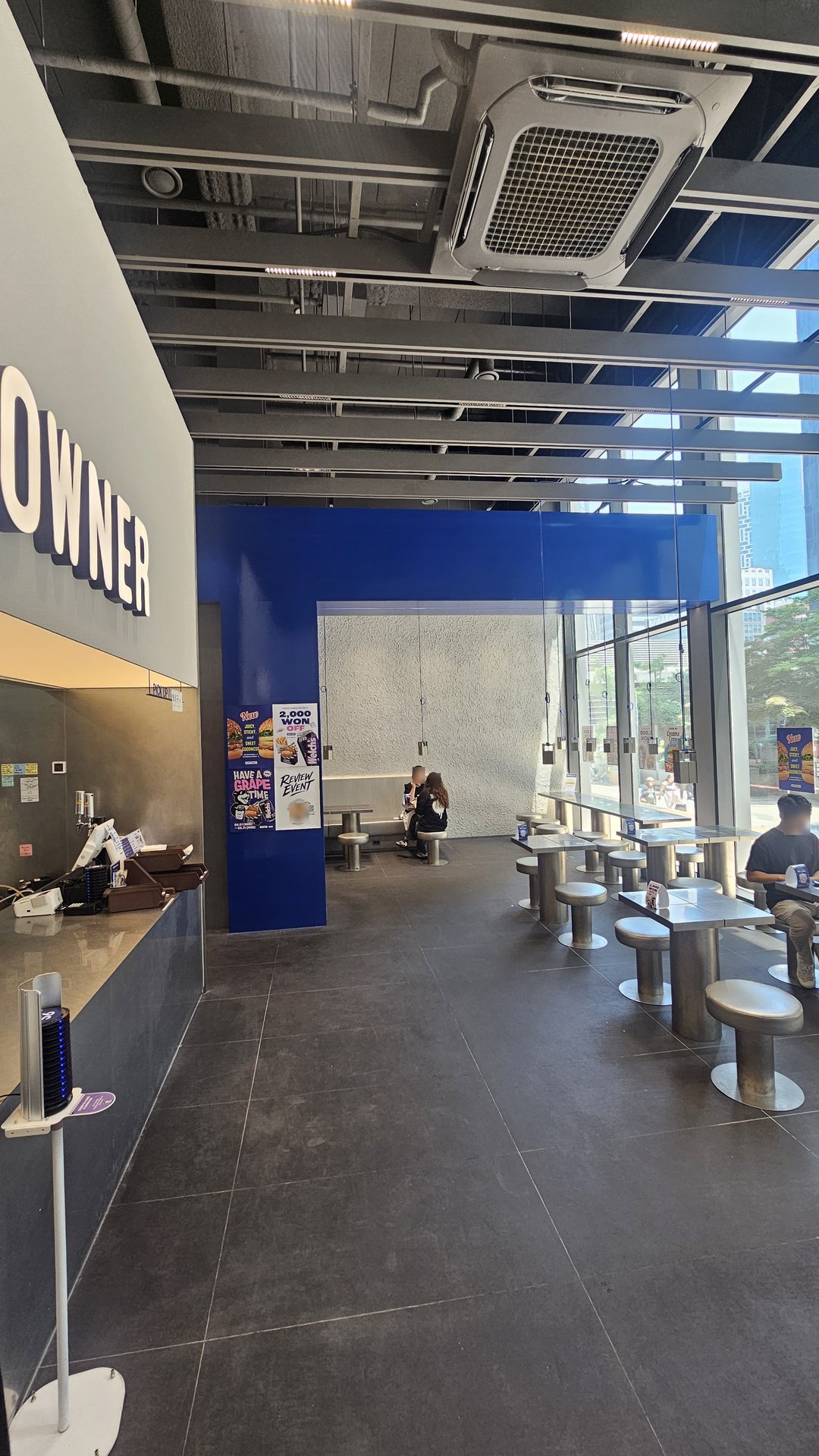 Downtowner Yeouido interior with blue accent decor, bar stools, and DOWNTOWNER neon sign above counter