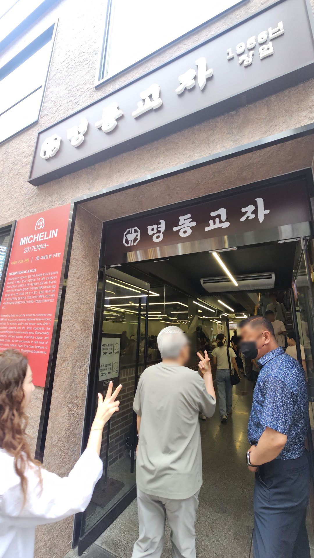Myeongdong Gyoja main branch entrance with Michelin Guide sign and crowd waiting outside