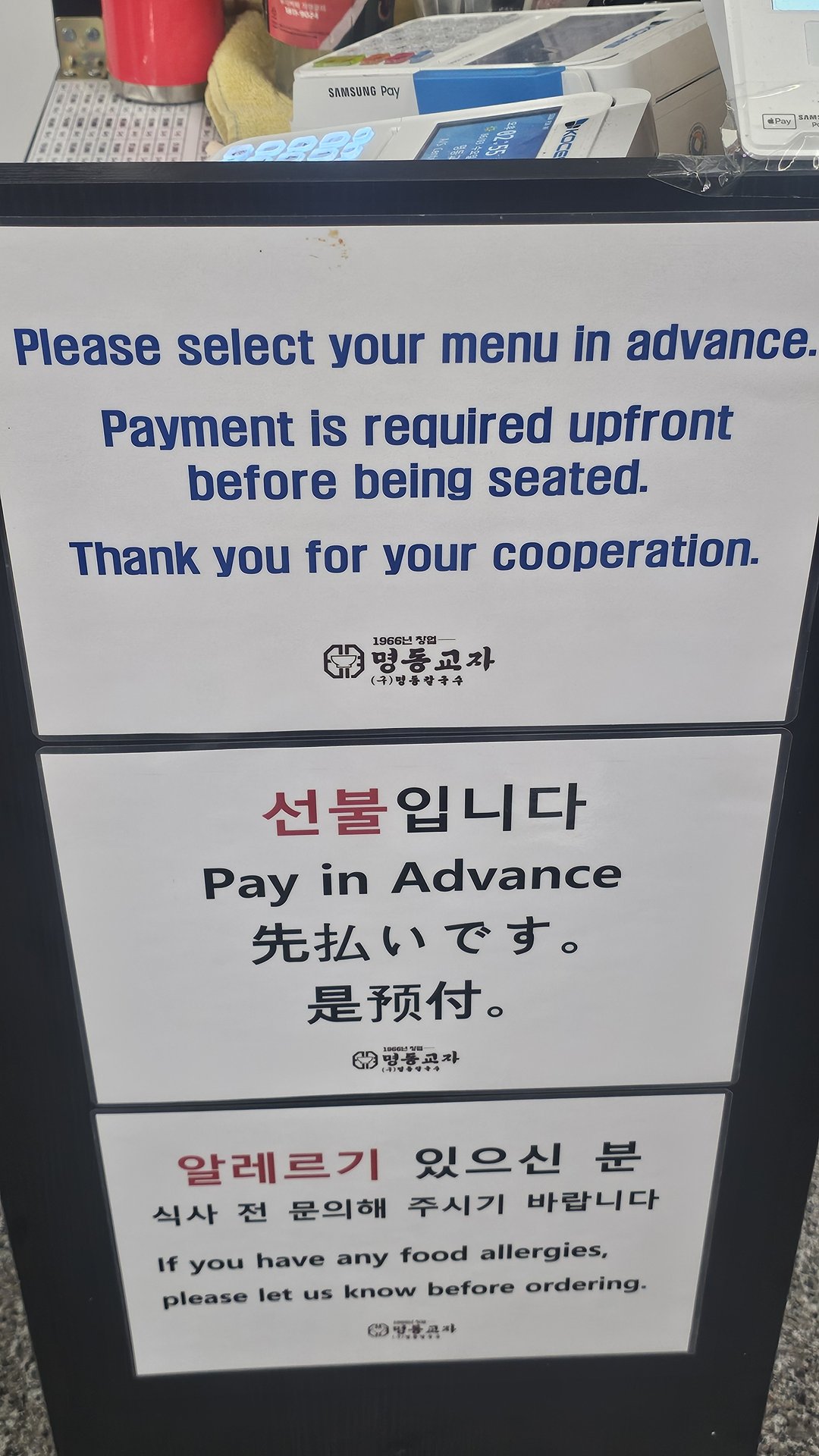 Trilingual pre-payment policy notice in Korean English and Japanese at Myeongdong Gyoja entrance