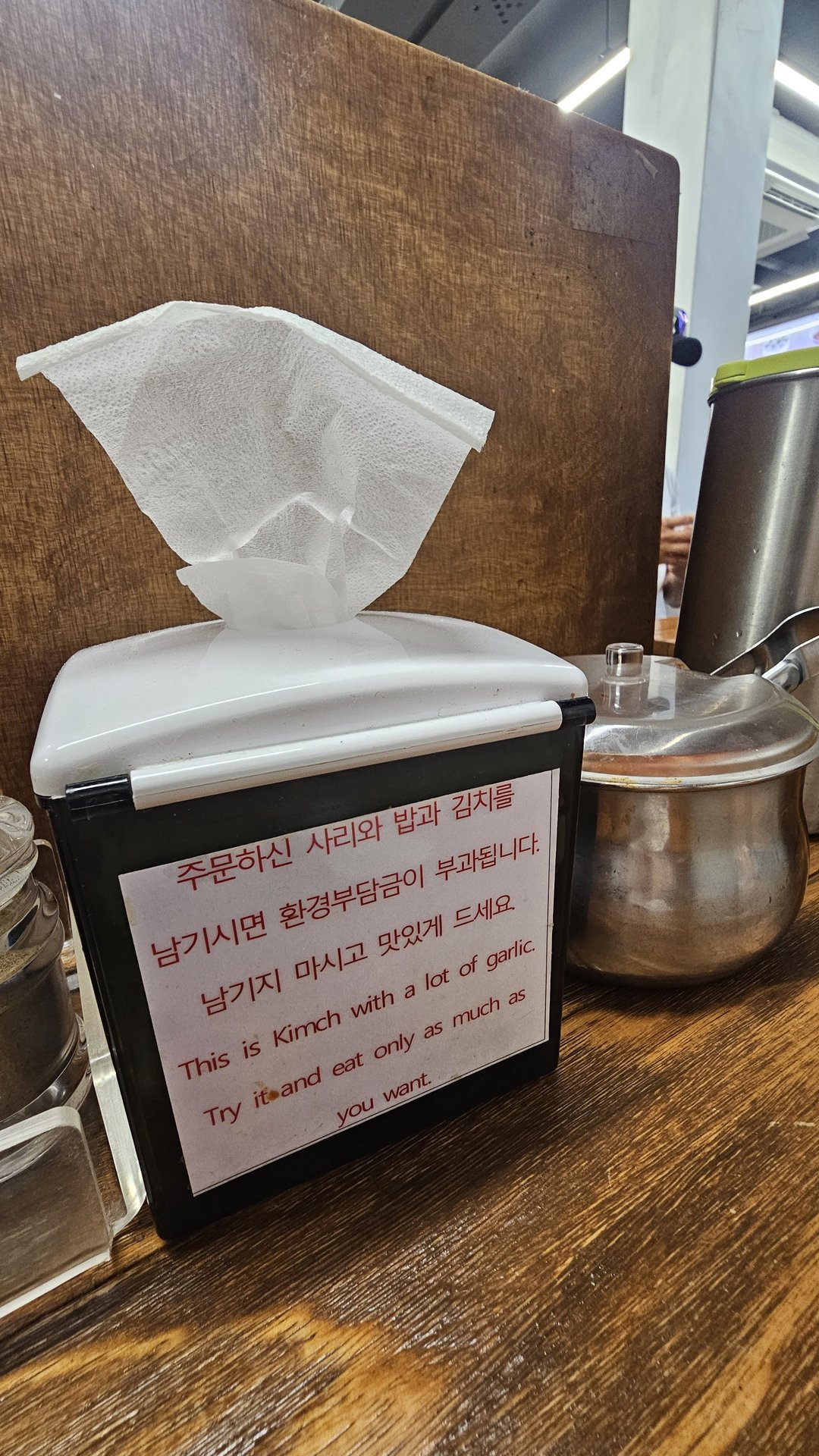 Table notice at Myeongdong Gyoja warning that kimchi contains a lot of garlic in English and Korean