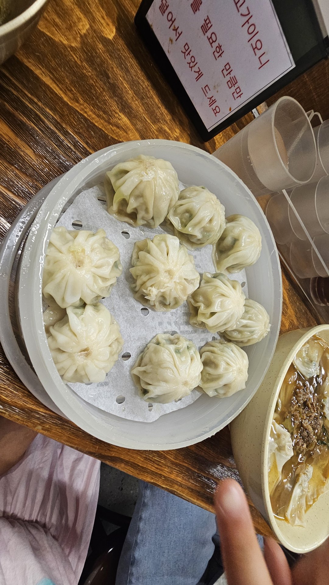 Steamed mandu dumplings in bamboo steamer alongside kalguksu noodle soup at Myeongdong Gyoja