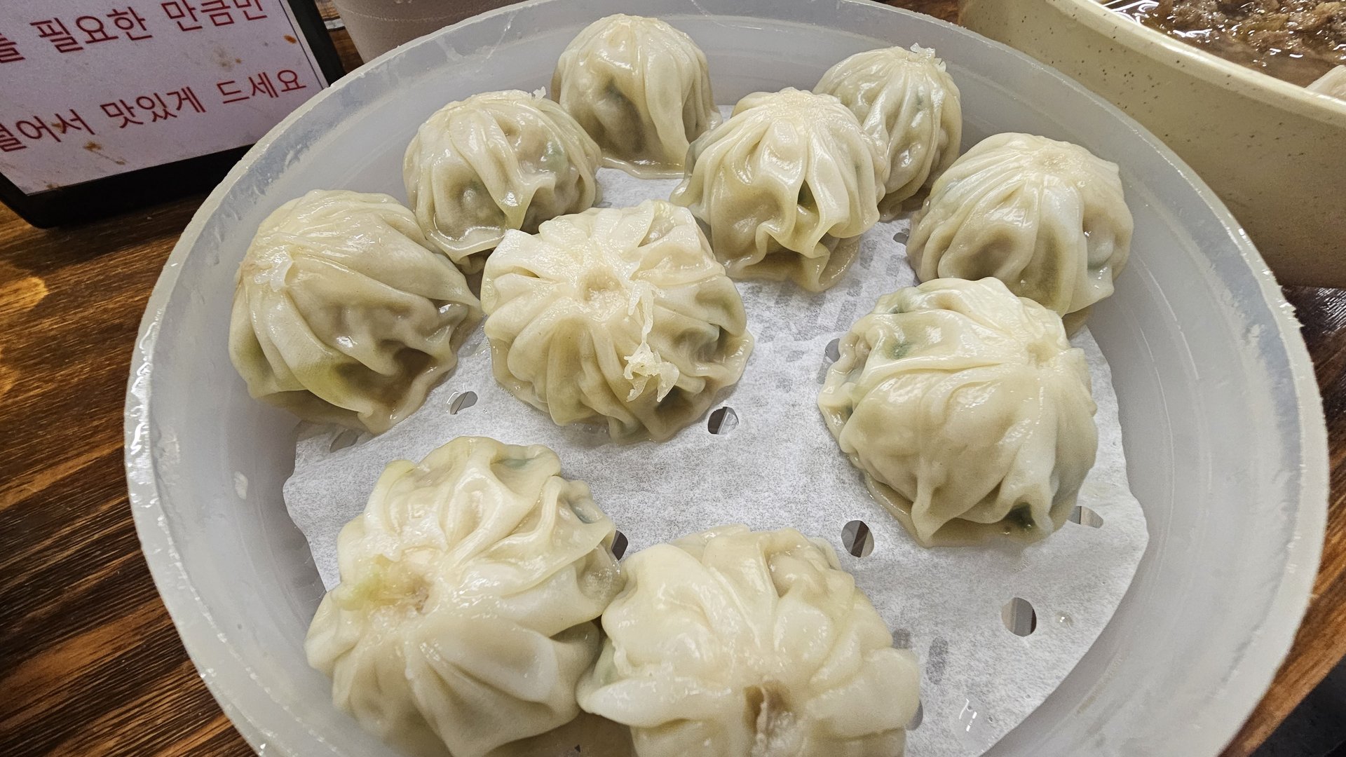 Closeup of nine steamed mandu dumplings in bamboo steamer at Myeongdong Gyoja