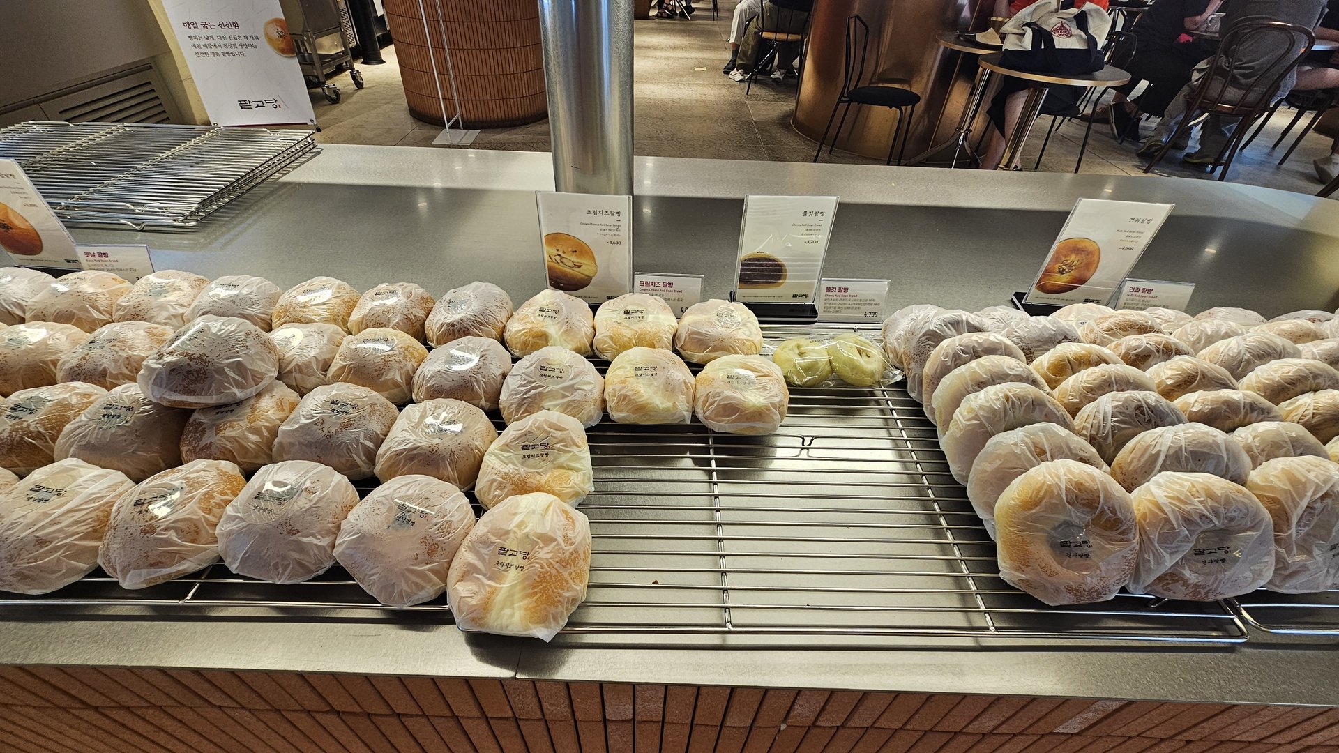 Full display of multiple red bean bread varieties at Patgodang counter with price tags and variety labels