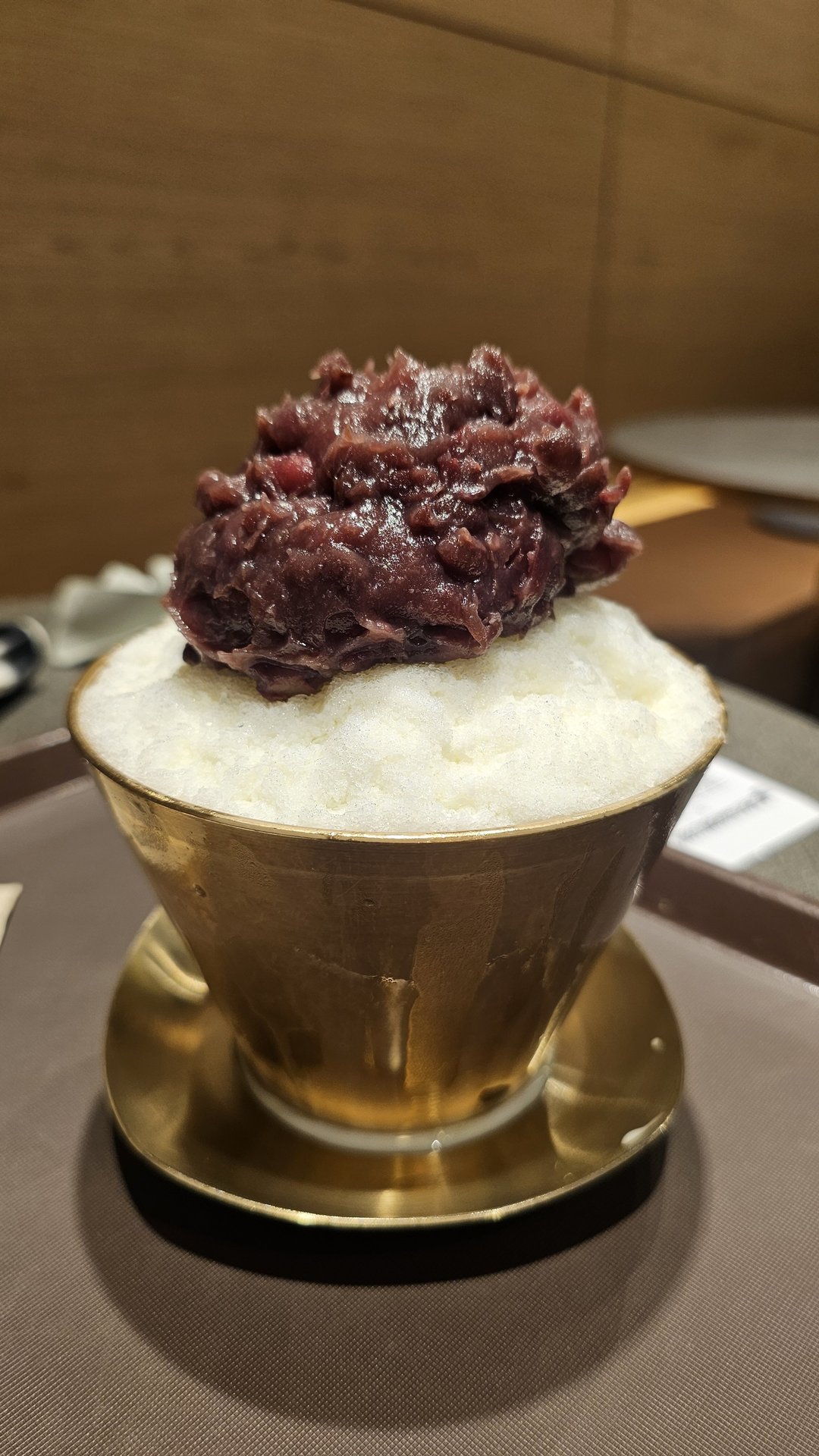 Side view of red bean bingsu in brass bowl at Patgodang Myeongdong showing fluffy snow ice and generous red bean topping