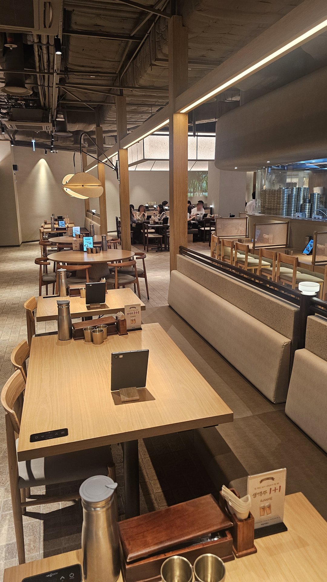 Spacious interior of Jeil Myeonso Yeouido with wooden tables and open kitchen visible in the background