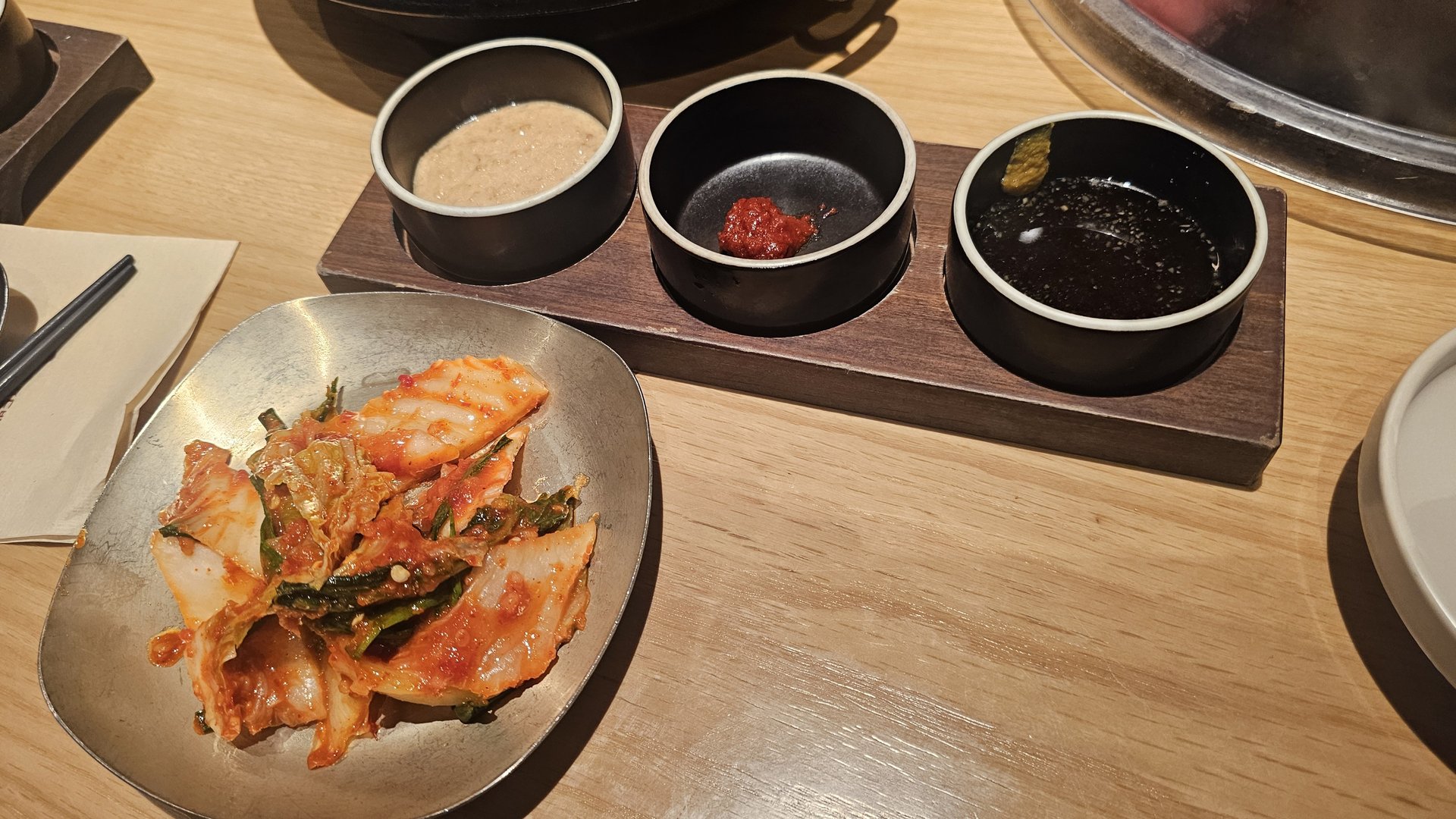 Side dishes at Jeil Myeonso — kimchi and three dipping sauces including sesame, gochujang, and soy sauce
