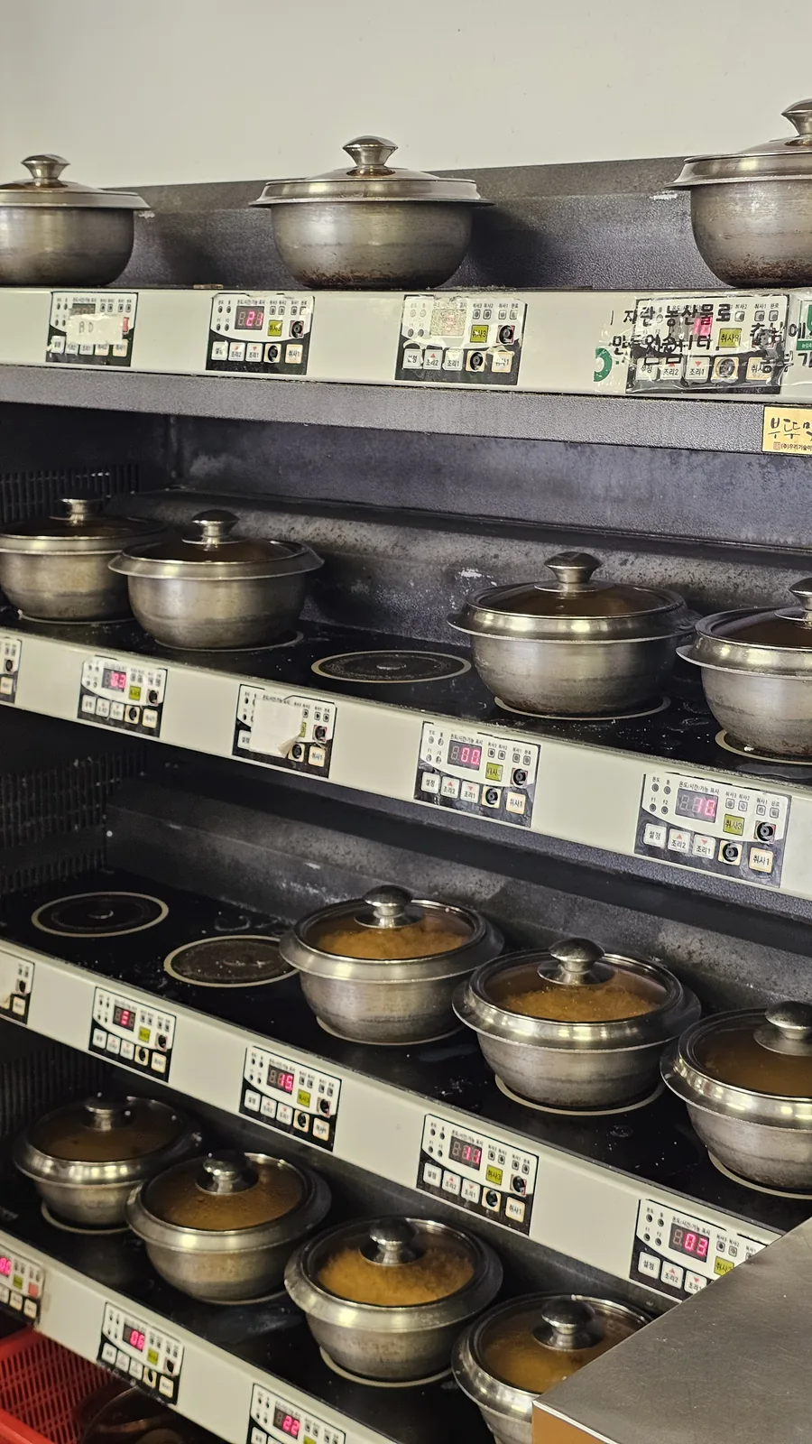 Stone pot rice cooking station at Nongbu Bapsang with multiple dolsot pots steaming on induction units simultaneously