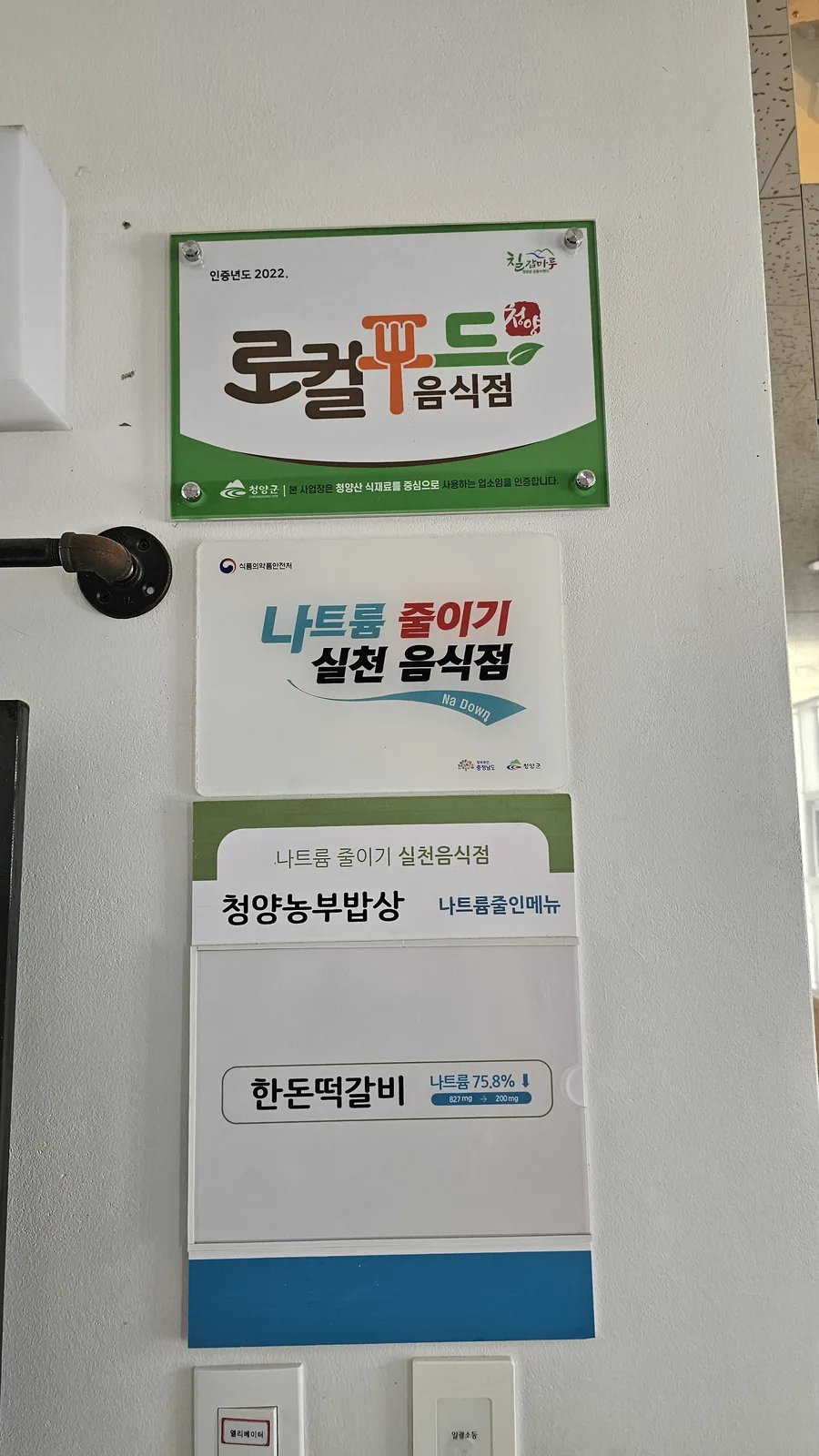 Local food restaurant certification plaque and low-sodium achievement award displayed at Nongbu Bapsang entrance
