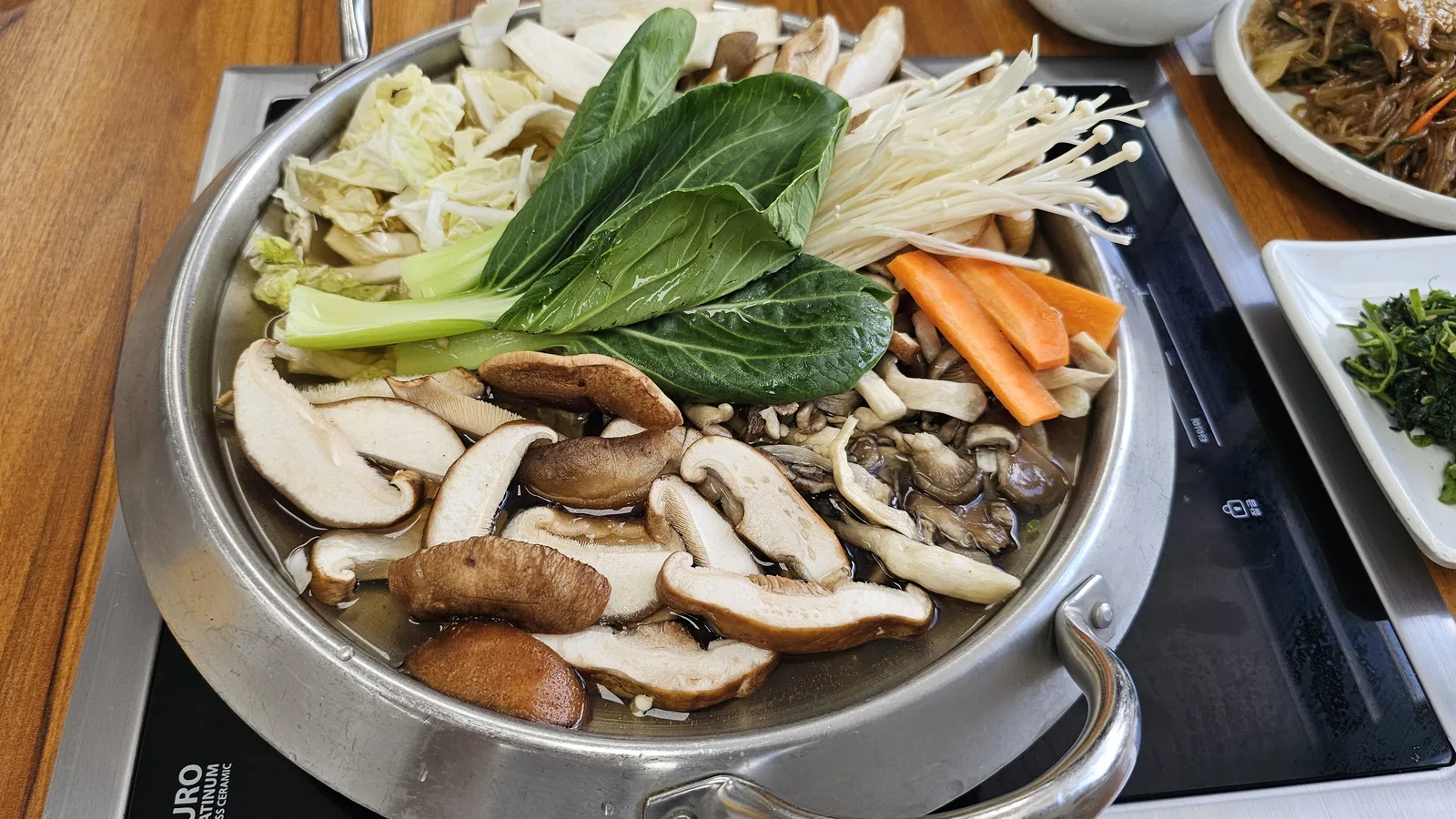 Mushroom jeongol pot at Nongbu Bapsang before cooking loaded with shiitake, oyster mushrooms, enoki, bok choy, and napa cabbage
