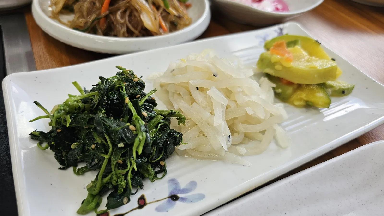 Nongbu Bapsang three-banchan plate with chive namul, shredded radish, and cucumber salad from alternate angle