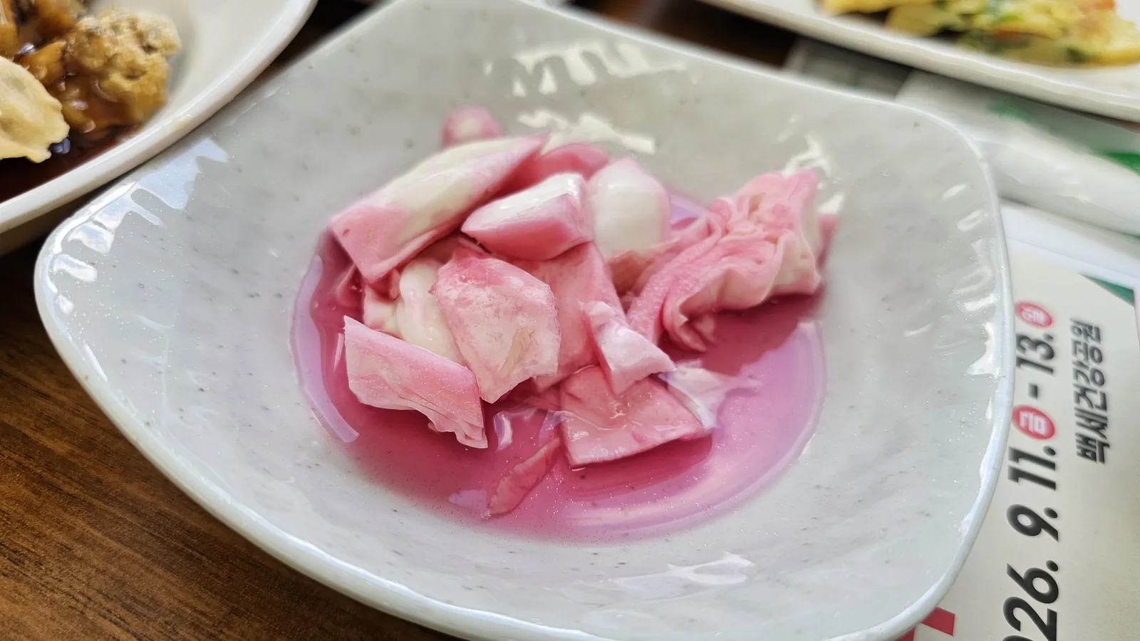 Pink pickled vegetables banchan at Nongbu Bapsang — sweet-tangy pickled onion or radish in light brine