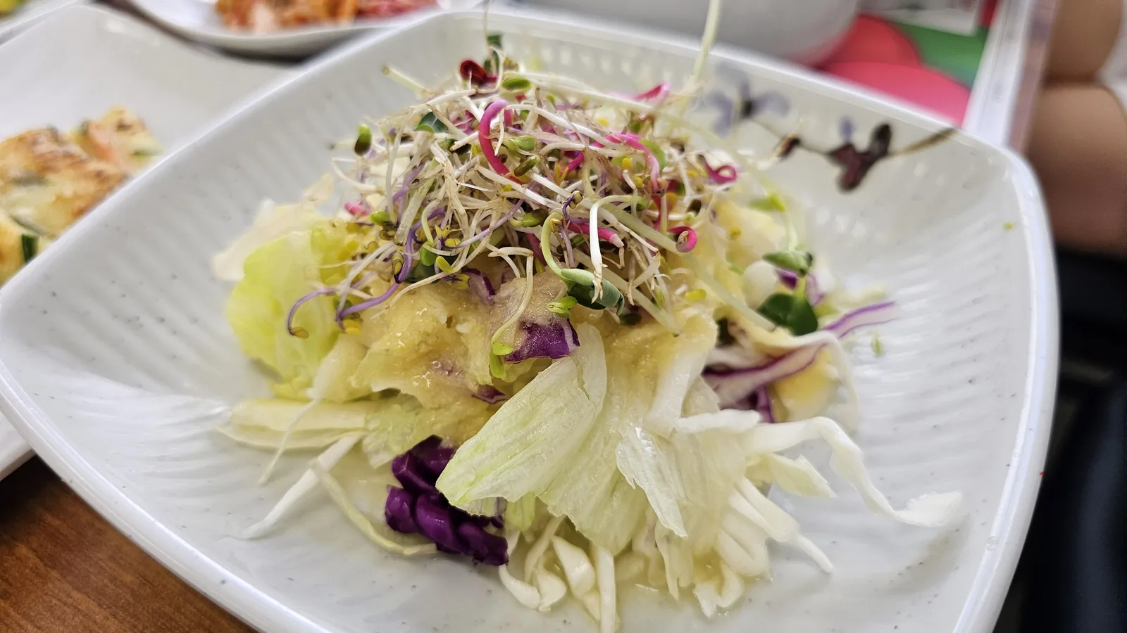 Fresh sprout salad at Nongbu Bapsang with romaine, red cabbage, mixed microgreens, and light dressing