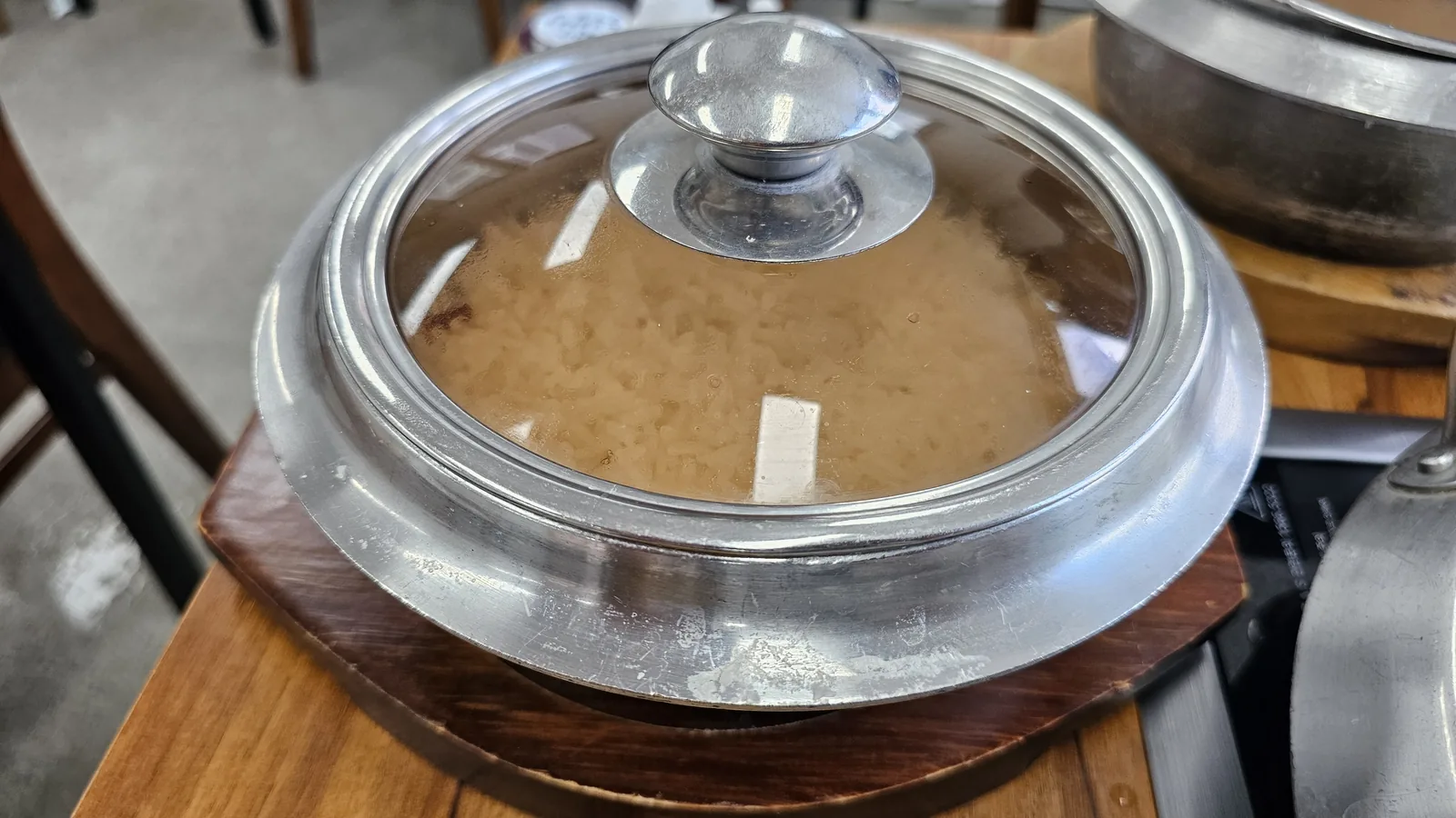 Goji berry stone pot rice at Nongbu Bapsang with glass lid on showing steaming white rice cooking inside
