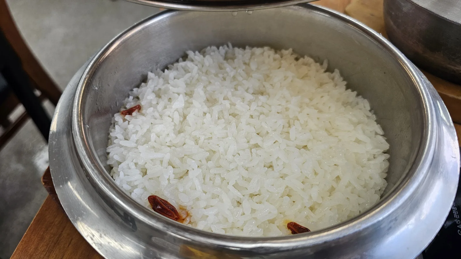 Goji berry stone pot rice at Nongbu Bapsang with lid removed revealing fluffy white rice dotted with red goji berries